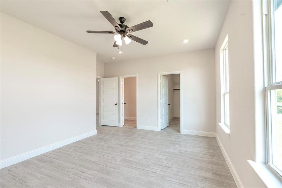 Unfurnished bedroom with a walk in closet, connected bathroom, a closet, and ceiling fan