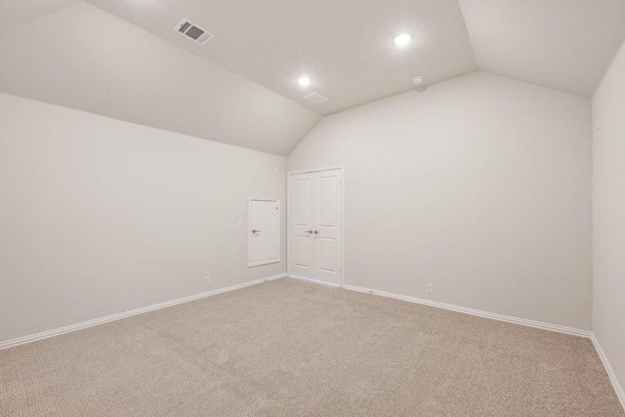 Empty bedroom with vaulted ceiling, beige carpet, and two white doors Empty bedroom with vaulted ceiling, beige carpet, and two white doors