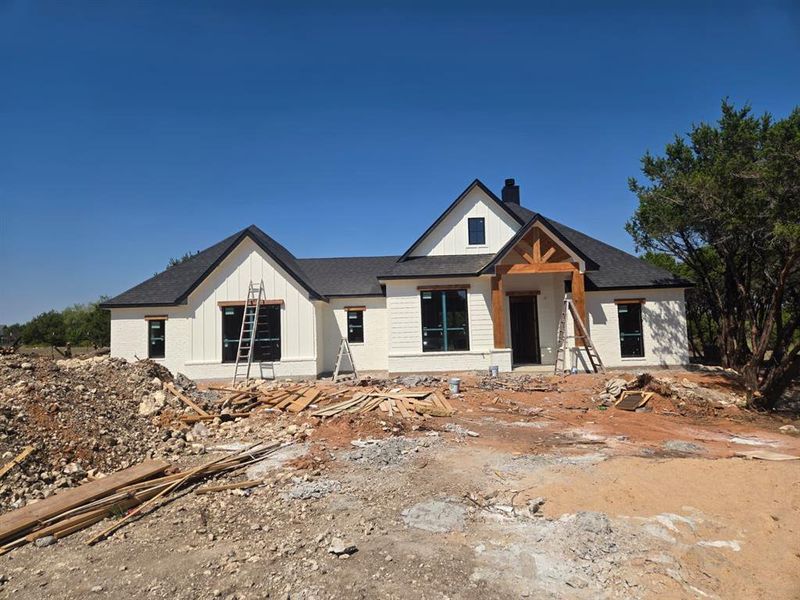 Modern farmhouse style home with a chimney, roof with shingles, and board and batten siding Modern farmhouse style home with a chimney, roof with shingles, and board and batten siding