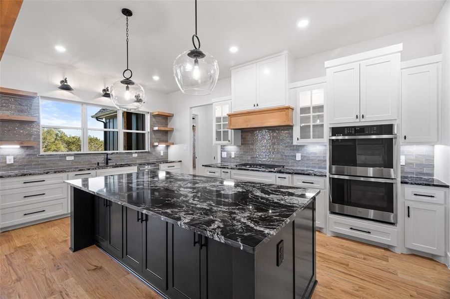 Kitchen featuring backsplash, a center island, light wood-type flooring, and stainless steel appliances