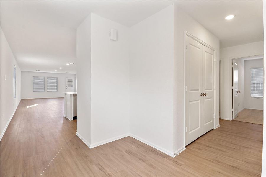 Bright, open interior layout featuring durable wood-style flooring, neutral finishes, and smooth flow from the hallway into the main living and kitchen areas Bright, open interior layout featuring durable wood-style flooring, neutral finishes, and smooth flow from the hallway into the main living and kitchen areas