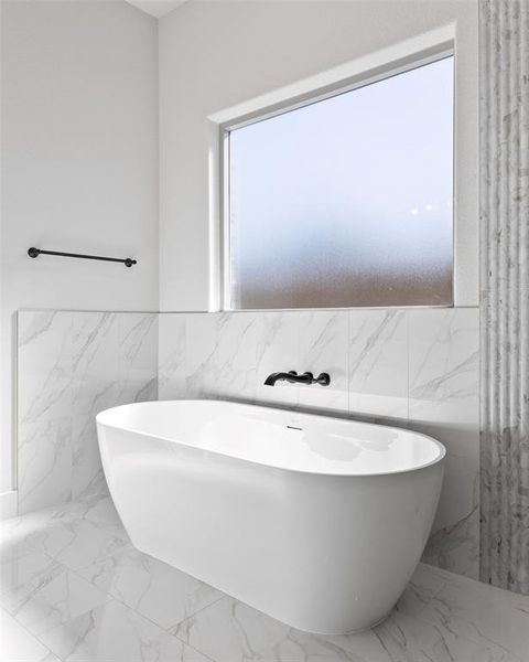 Freestanding soaking tub with a wall-mounted matte black faucet Freestanding soaking tub with a wall-mounted matte black faucet