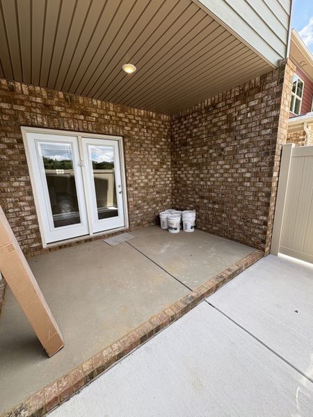 Covered back patio with white vinyl fence and storage closet
