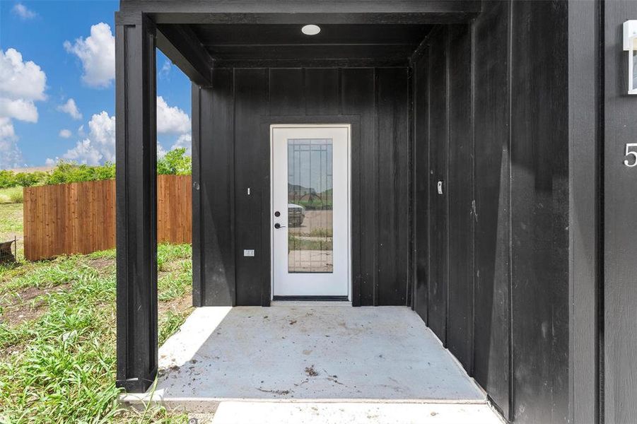 Doorway to property featuring board and batten siding and a patio area