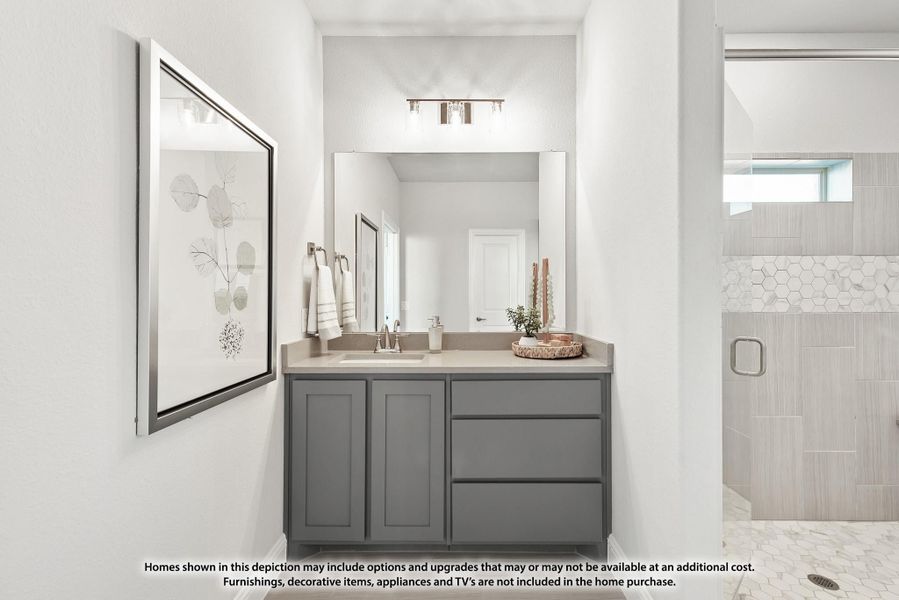 Bathroom vanity with gray cabinets, beige countertop, and large mirror next to a tiled walk-in shower Bathroom vanity with gray cabinets, beige countertop, and large mirror next to a tiled walk-in shower
