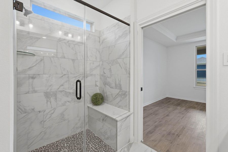 Marble-patterned tile, a built-in shower bench and natural light elevate this bathroom into a true retreat.