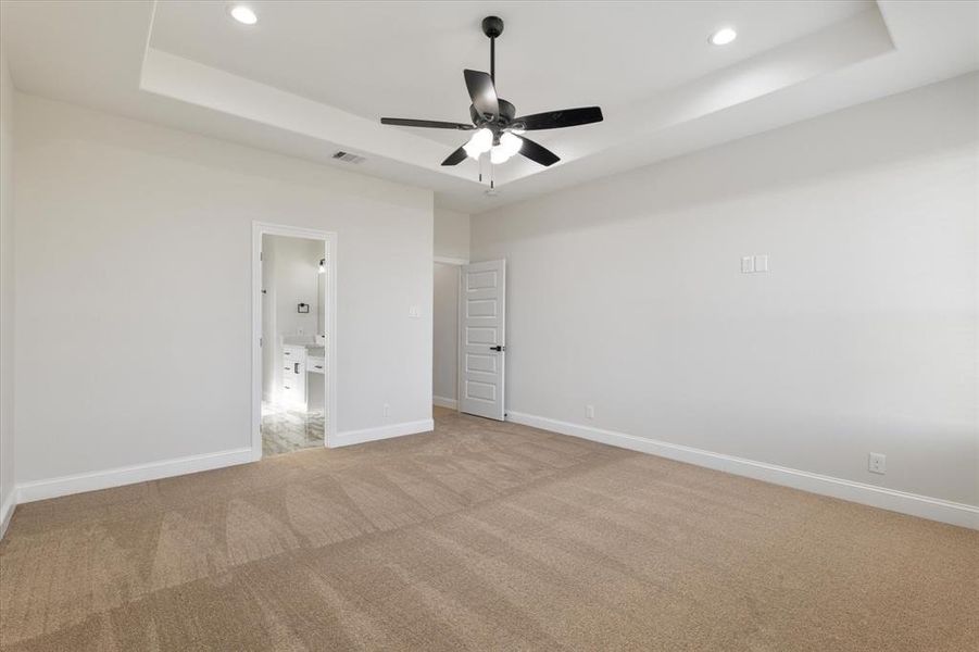 Unfurnished bedroom with a raised ceiling, visible vents, and baseboards