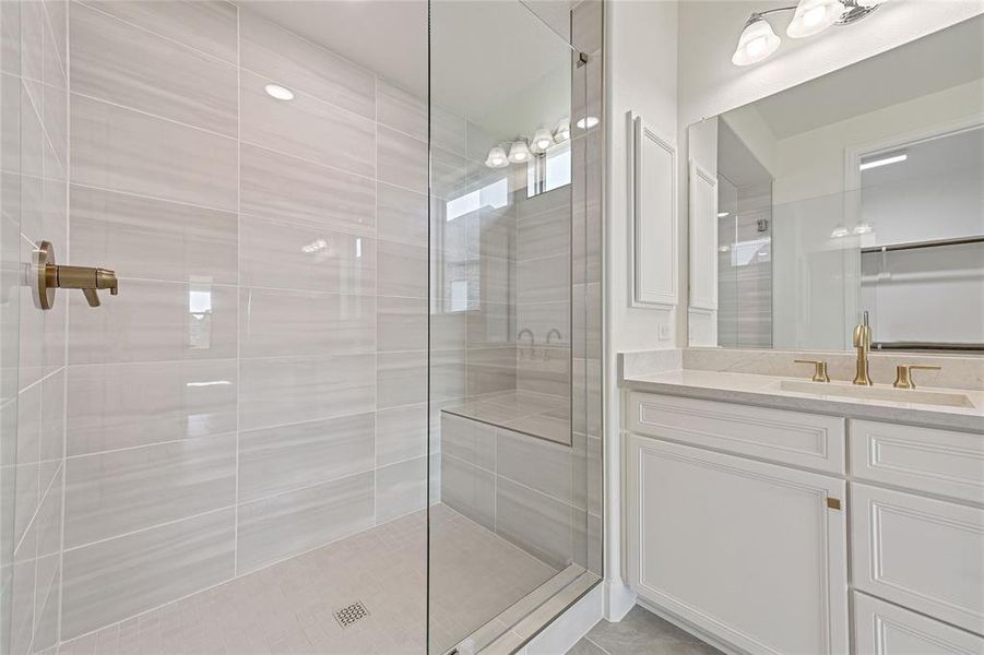 Bathroom featuring a tile shower and vanity