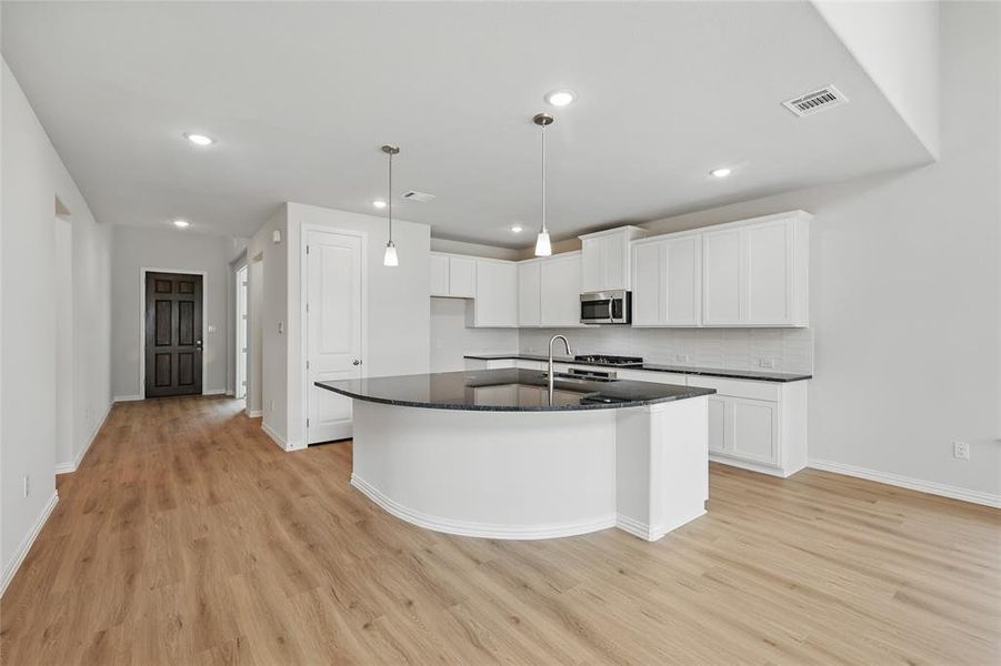 Kitchen featuring visible vents, light wood-type flooring, baseboards, and stainless steel microwave Kitchen featuring visible vents, light wood-type flooring, baseboards, and stainless steel microwave