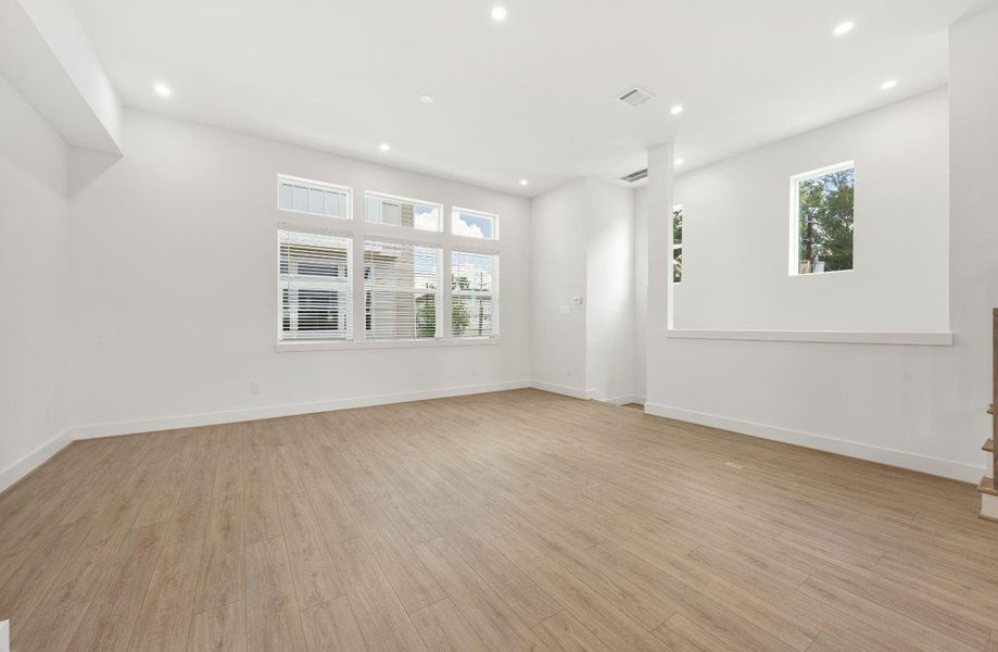 Bright, open, and airy, the main living area features tall ceilings, abundant windows, recessed lighting, and warm wood-look flooring. The flexible layout allows for multiple furniture arrangements and creates an inviting backdrop for gatherings, relaxing evenings, or stylish everyday living.