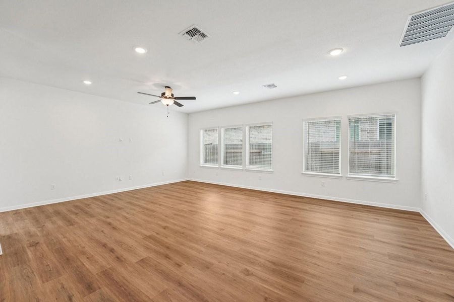 An open living area presents rich wood flooring and ample natural light through a wall of windows. An open living area presents rich wood flooring and ample natural light through a wall of windows.