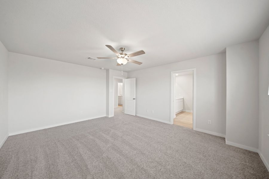 A room with a ceiling fan and a carpet.