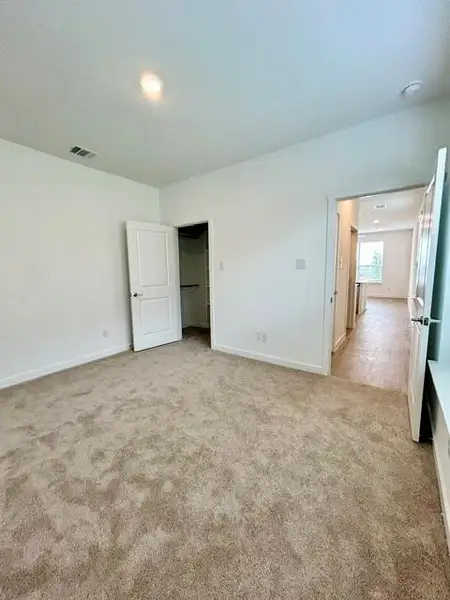 Spacious room featuring neutral-toned carpet flooring and white painted walls Spacious room featuring neutral-toned carpet flooring and white painted walls
