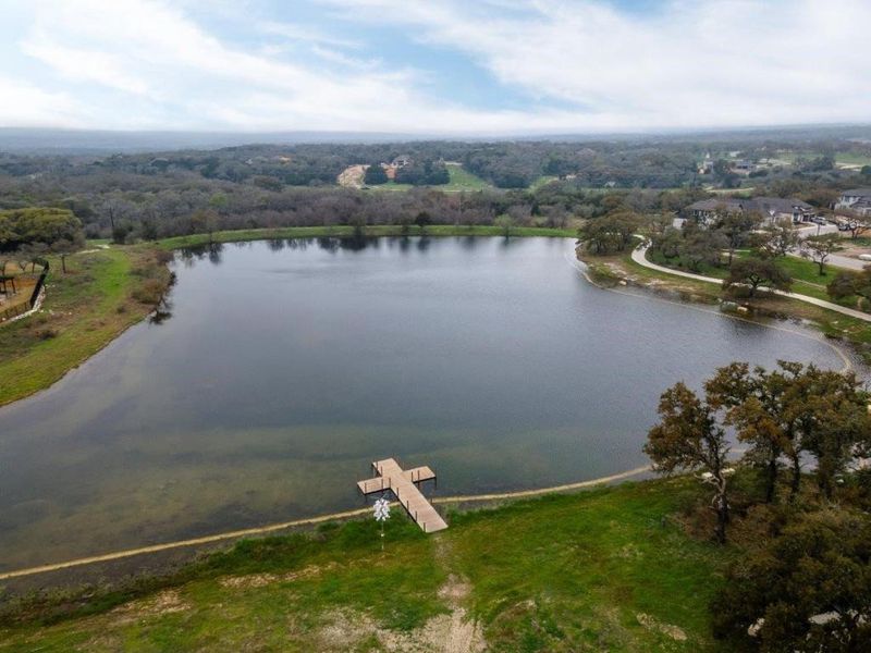 Tranquil lake with a wooden dock, surrounded by mature trees and natural landscaping
