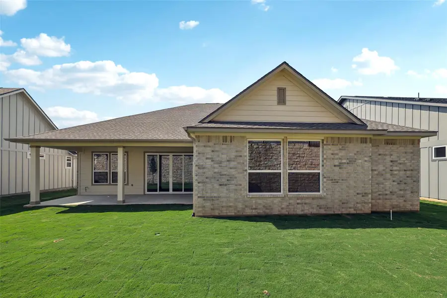 Back of property featuring brick siding, a shingled roof, a yard, and a patio