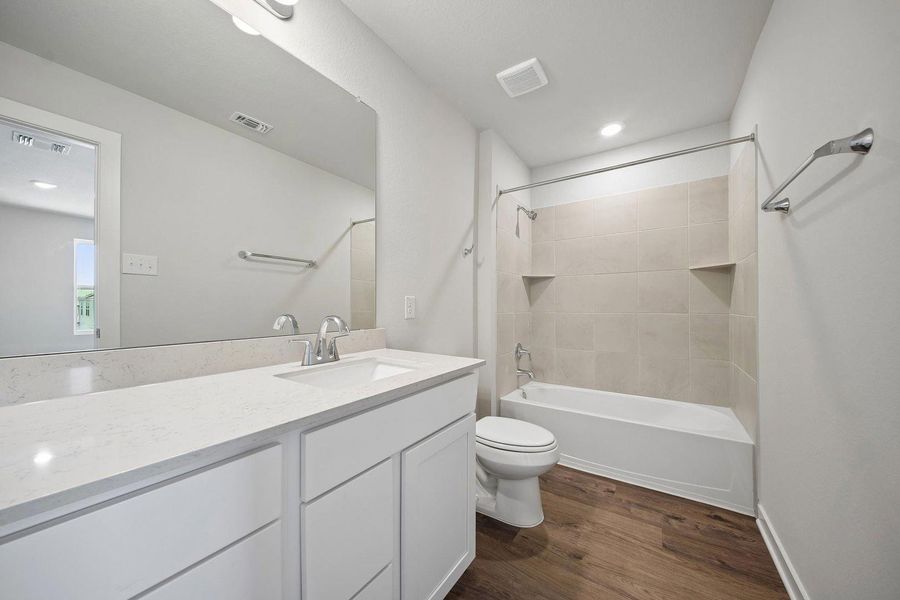 A well-appointed bathroom features a spacious vanity with an integrated sink and a tiled shower-tub combination. A well-appointed bathroom features a spacious vanity with an integrated sink and a tiled shower-tub combination.