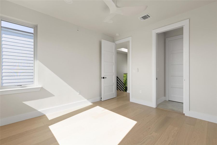 Natural light streams across smooth hardwood floors in this minimalist bedroom.