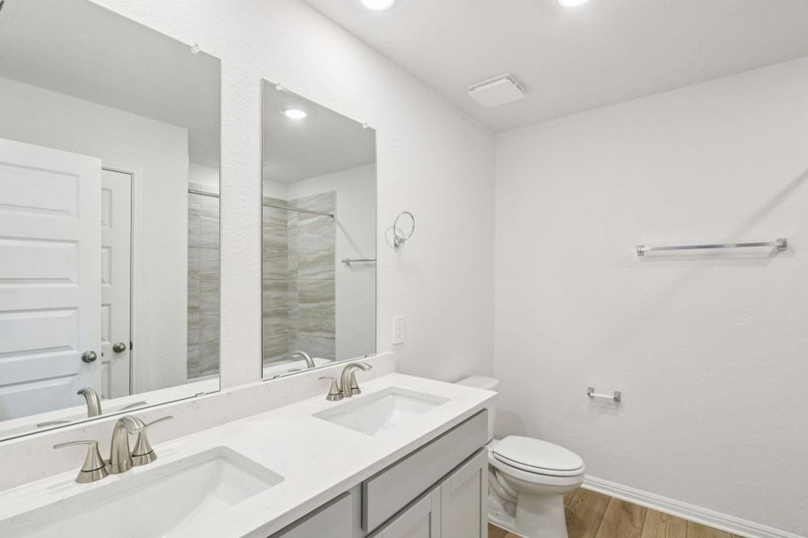Bathroom featuring light wood-type flooring, double vanity, a tile shower, and recessed lighting Bathroom featuring light wood-type flooring, double vanity, a tile shower, and recessed lighting