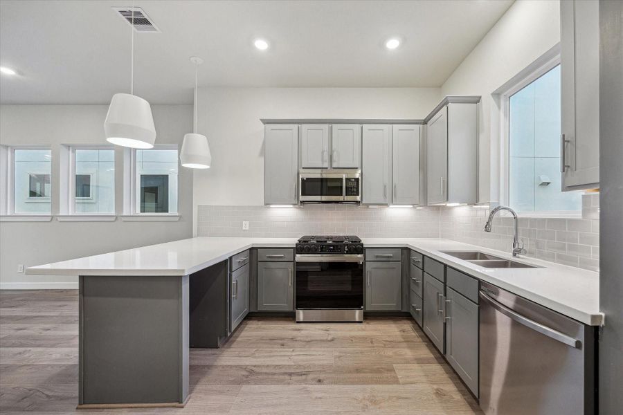 Open kitchen with large peninsula, quartz counters, and ample cabinetry.
