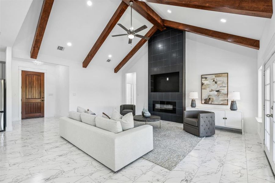 Living room with high vaulted ceiling, a fireplace, light tile patterned floors, and ceiling fan