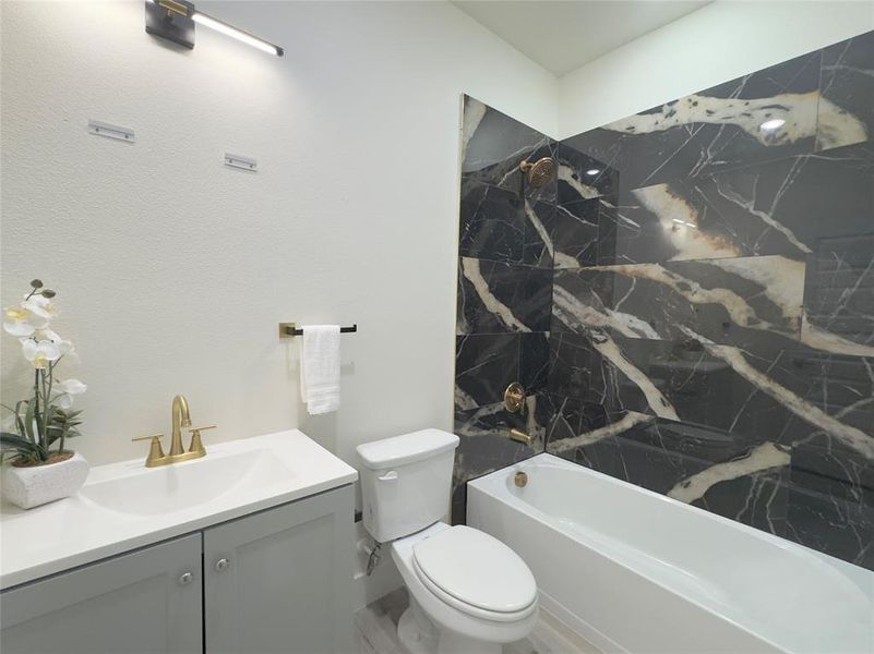 Full bathroom with toilet, tiled shower / bath combo, and vanity