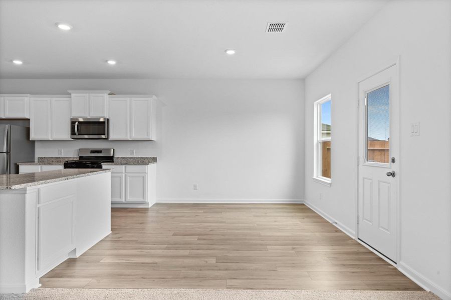 Kitchen with white cabinets, appliances with stainless steel finishes, light stone counters, light wood-style flooring, and recessed lighting Kitchen with white cabinets, appliances with stainless steel finishes, light stone counters, light wood-style flooring, and recessed lighting