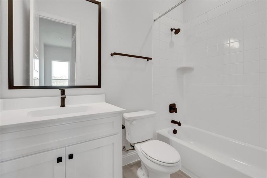 Full bathroom with tiled shower / bath combo, vanity, and toilet