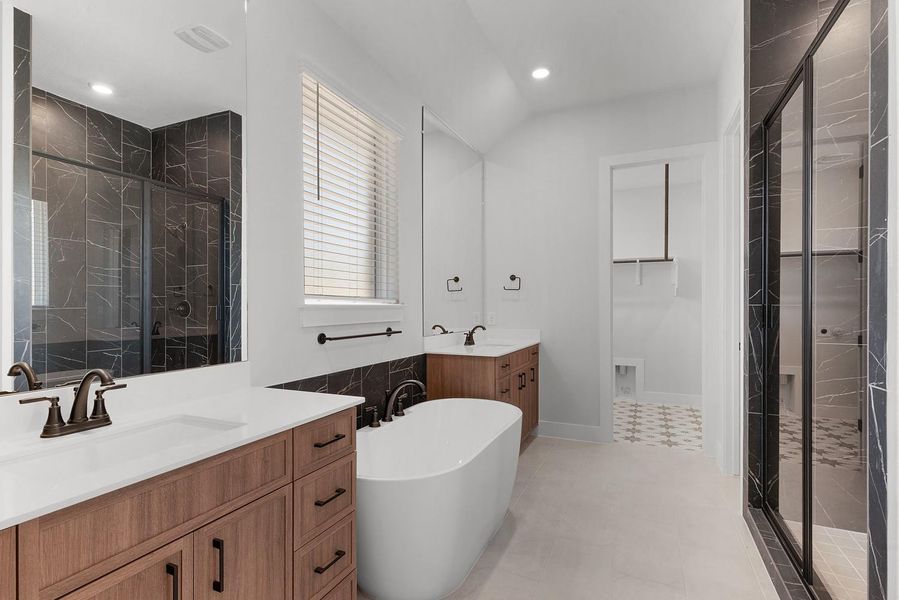 A well-appointed bath offers a sleek soaking tub and ample vanity space with elegant dark accents.