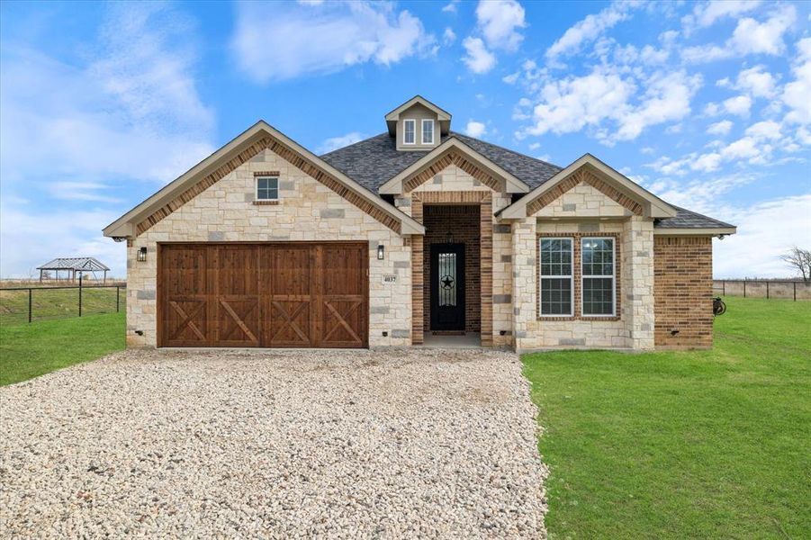 View of front of property with gravel driveway, fence, and a front yard