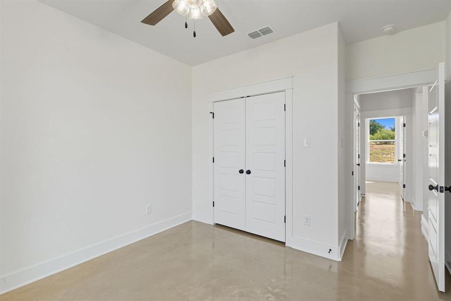 Unfurnished bedroom with finished concrete flooring, a closet, and a ceiling fan