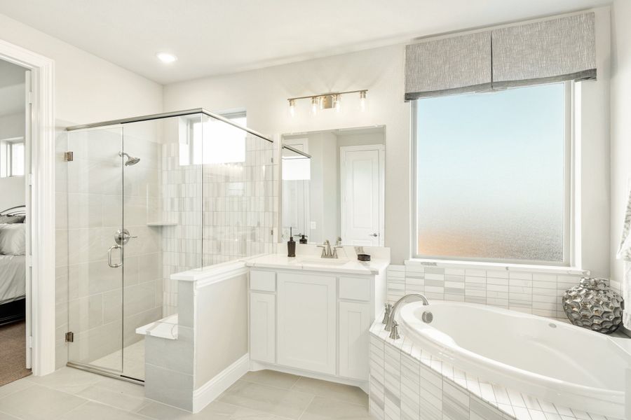 Master bathroom with glass walk-in shower, soaking tub, white vanity, and tile floors Master bathroom with glass walk-in shower, soaking tub, white vanity, and tile floors