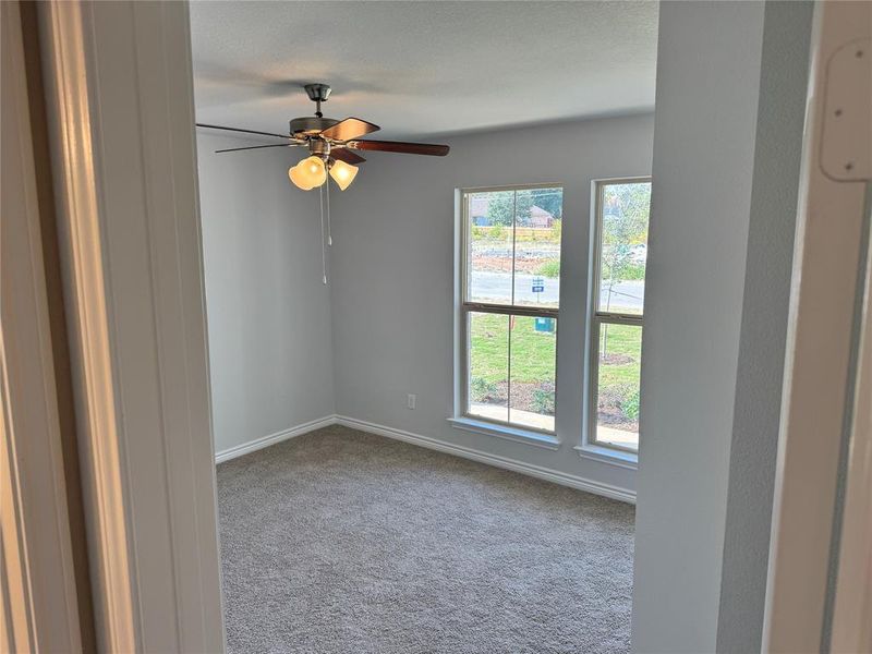 Empty room featuring carpet flooring and a ceiling fan