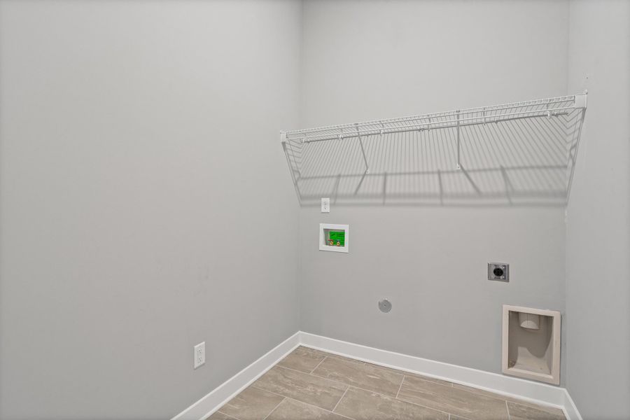 Dedicated utility space featuring light gray walls, white baseboards, a white wire shelf, and wood-finish flooring Dedicated utility space featuring light gray walls, white baseboards, a white wire shelf, and wood-finish flooring