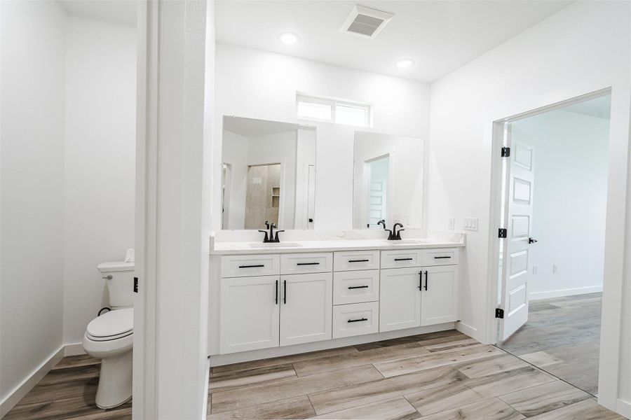 A sleek, contemporary bathroom offers twin vanities and wood-look tile flooring. A sleek, contemporary bathroom offers twin vanities and wood-look tile flooring.