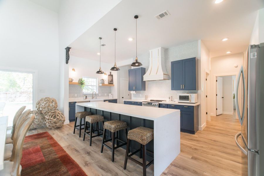 This kitchen is a chef’s delight, with elegant cabinetry, hardwood floors, a large island/breakfast bar, stainless steel appliances, and stone countertops, all highlighted by recessed lighting This kitchen is a chef’s delight, with elegant cabinetry, hardwood floors, a large island/breakfast bar, stainless steel appliances, and stone countertops, all highlighted by recessed lighting