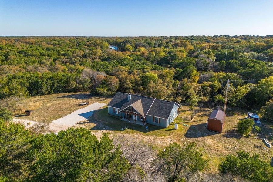 Aerial view of property and surrounding area featuring a forest