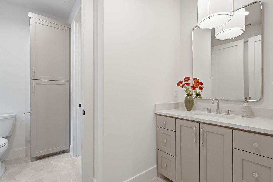Sleek vanity cabinetry and patterned tile flooring define this modern washroom space.
