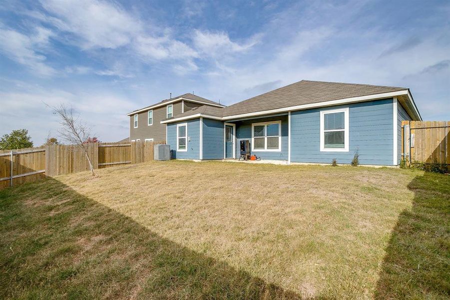 Rear view of house featuring a fenced backyard and a shingled roof