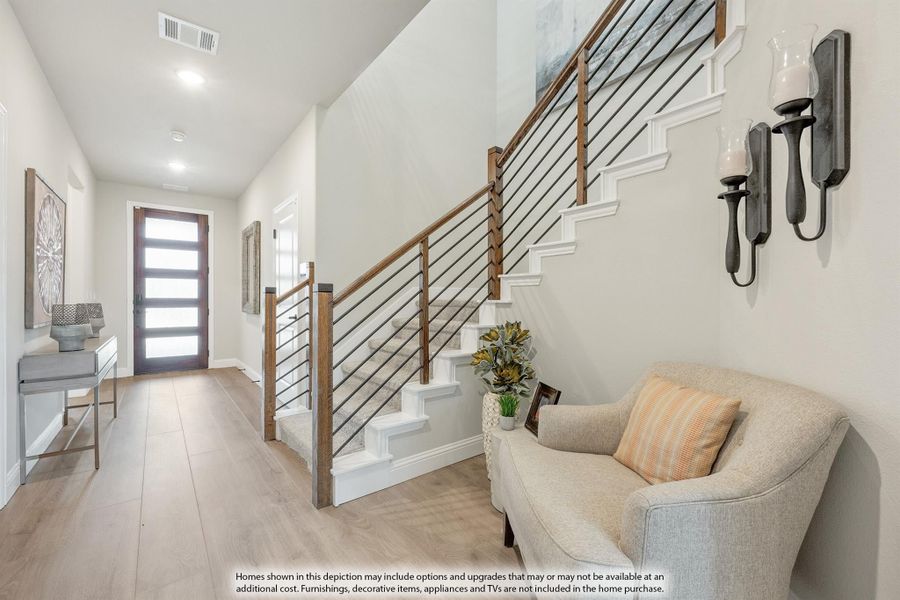 Bright entryway with wood and metal staircase railing, hardwood floors, and glass front door Bright entryway with wood and metal staircase railing, hardwood floors, and glass front door