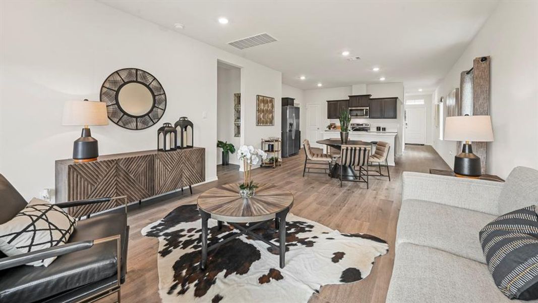 Open-concept living space featuring wood-finish flooring, recessed lighting, white walls, and a contemporary dark wood sideboard