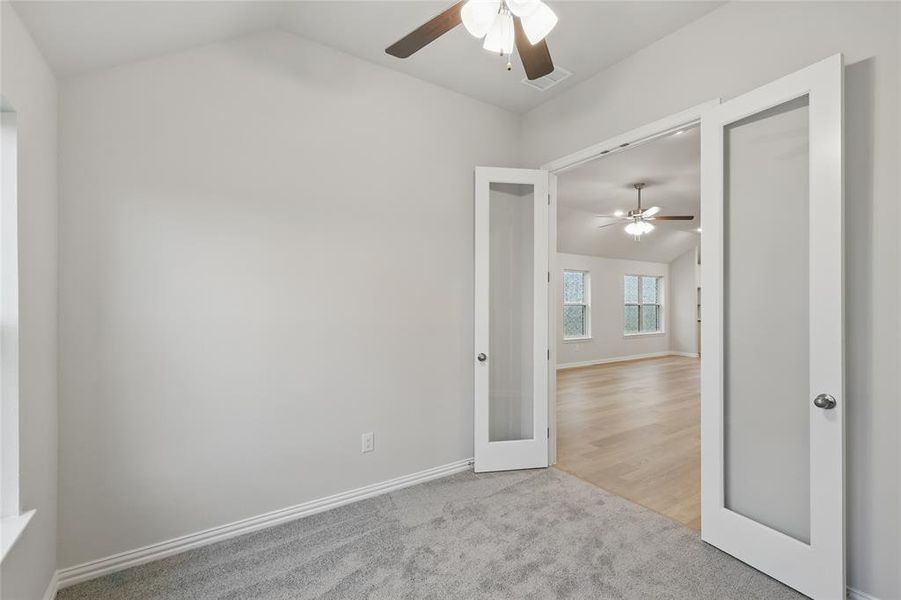 Empty room with lofted ceiling, a ceiling fan, and light colored carpet Empty room with lofted ceiling, a ceiling fan, and light colored carpet