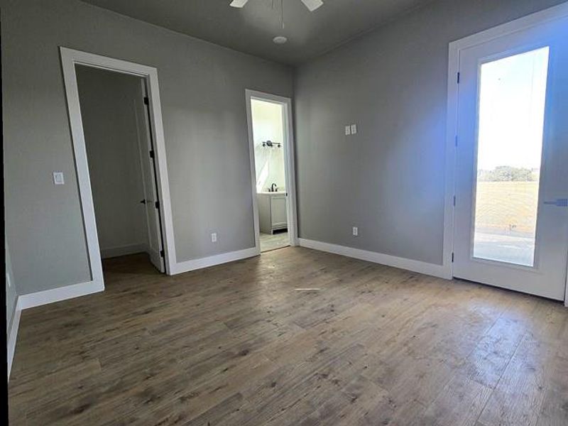 Unfurnished bedroom featuring hardwood / wood-style floors, a walk in closet, and ceiling fan