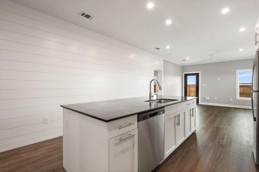Kitchen featuring appliances with stainless steel finishes, recessed lighting, dark wood-style flooring, white cabinets, and a kitchen island with sink