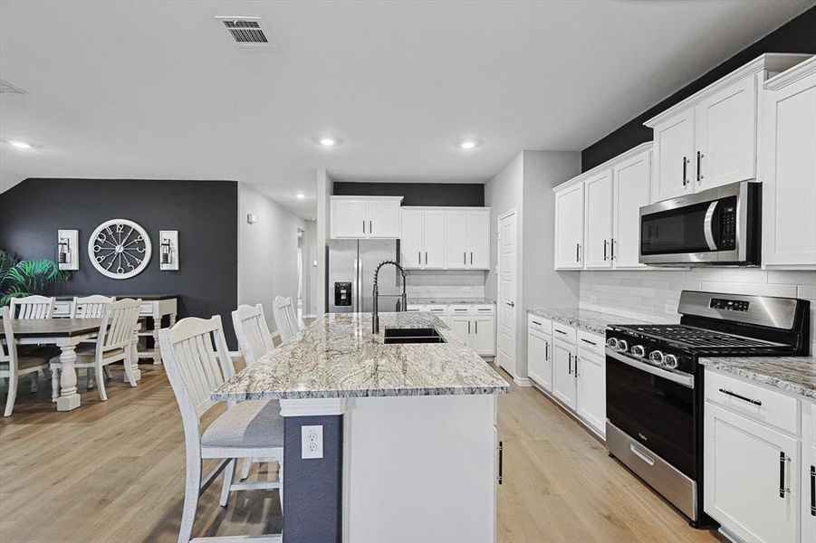 Kitchen featuring white cabinetry, appliances with stainless steel finishes, a kitchen island with sink, and sink