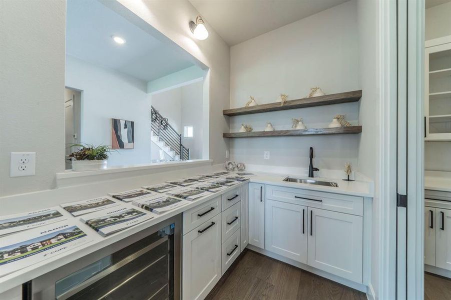 Kitchen featuring light countertops, wine cooler, dark wood-type flooring, white cabinets, and open shelves Kitchen featuring light countertops, wine cooler, dark wood-type flooring, white cabinets, and open shelves