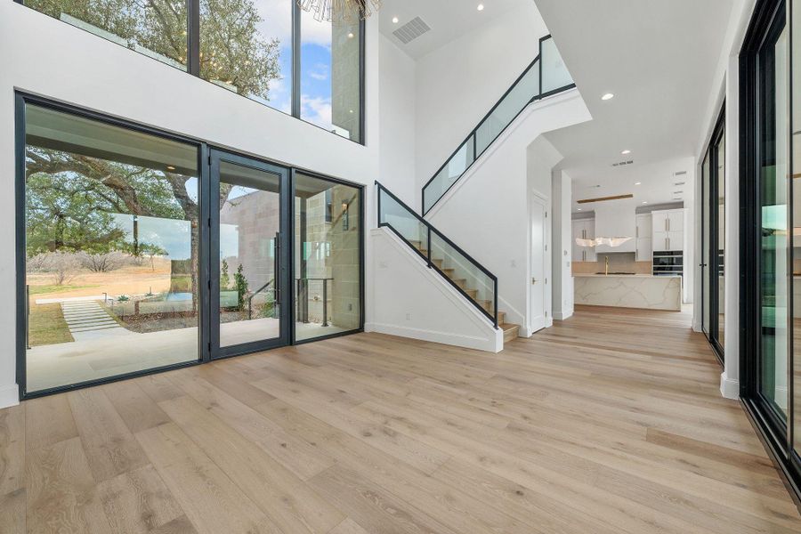 Unfurnished living room featuring a high ceiling, light wood-style floors, and recessed lighting