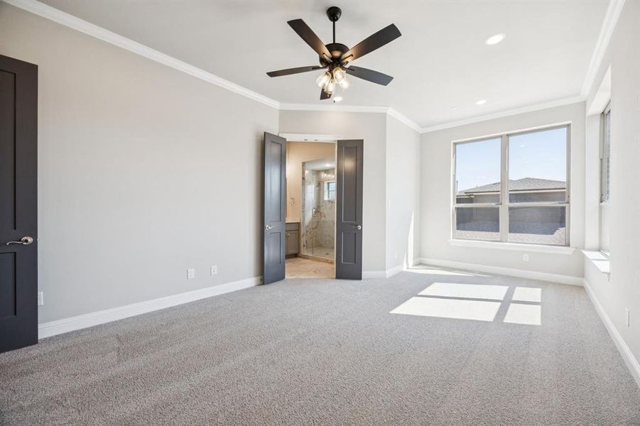 Spacious primary bedroom with seating area near windows. Spacious primary bedroom with seating area near windows.