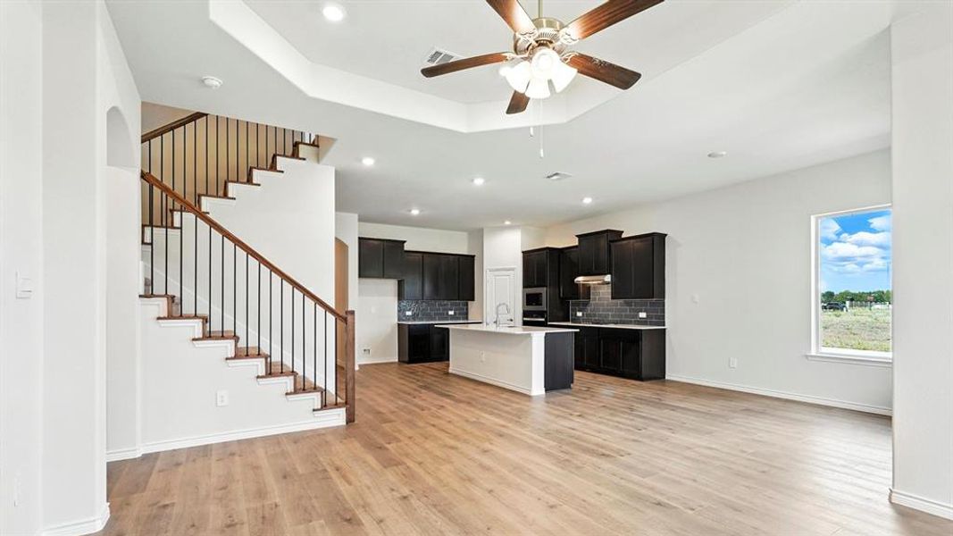 Kitchen featuring an island with sink, dark cabinetry, recessed lighting, tasteful backsplash, and ceiling fan
