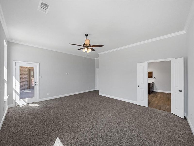 Prior listing photo. Property remains accurate - Spare room featuring dark colored carpet, a ceiling fan, and ornamental molding