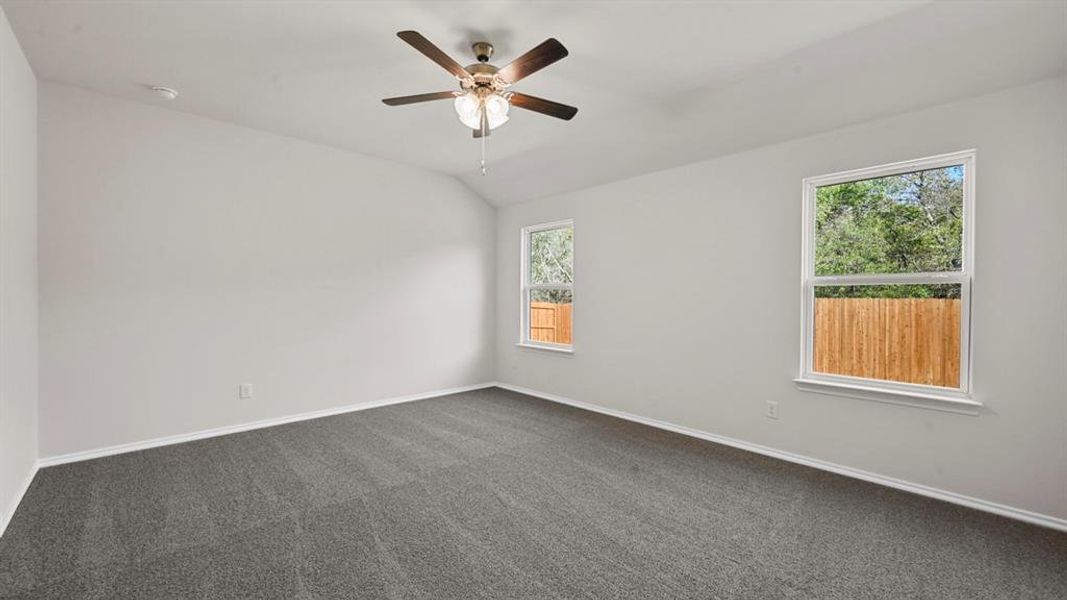 Spacious room featuring gray carpeting, light-colored walls, and a ceiling fan with integrated lighting Spacious room featuring gray carpeting, light-colored walls, and a ceiling fan with integrated lighting